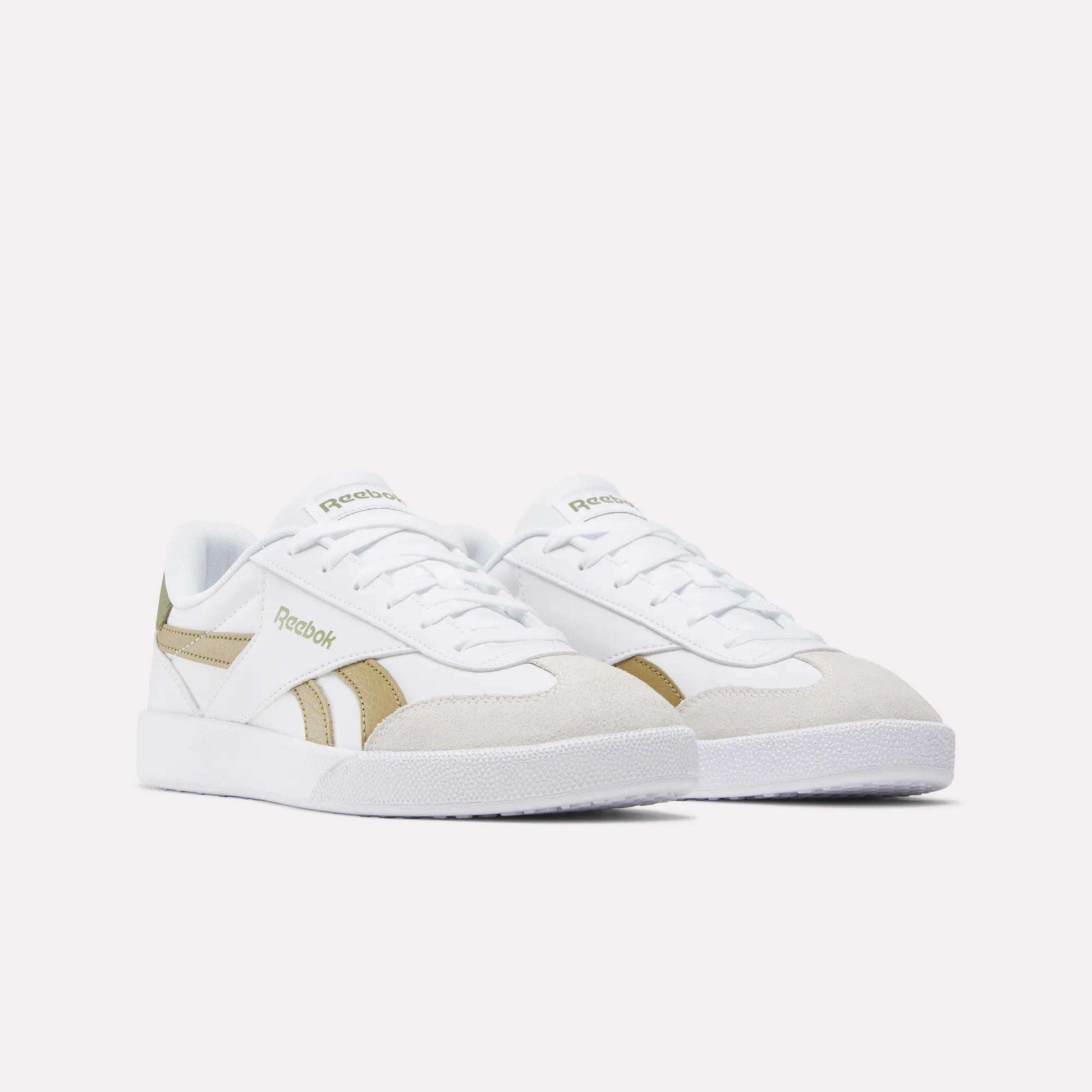 A pair of Reebok Smash Edge Shoes in white, featuring beige suede T-toe accents and gold side detailing, shown on a plain light background.