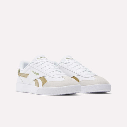 A pair of Reebok Smash Edge Shoes in white, featuring beige suede T-toe accents and gold side detailing, shown on a plain light background.