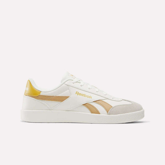 The Reebok Smash Edge Shoes feature a white design with beige and gold accents and the Reebok logo on the side and heel—ideal for fans of classic indoor soccer style, shown against a plain white background.