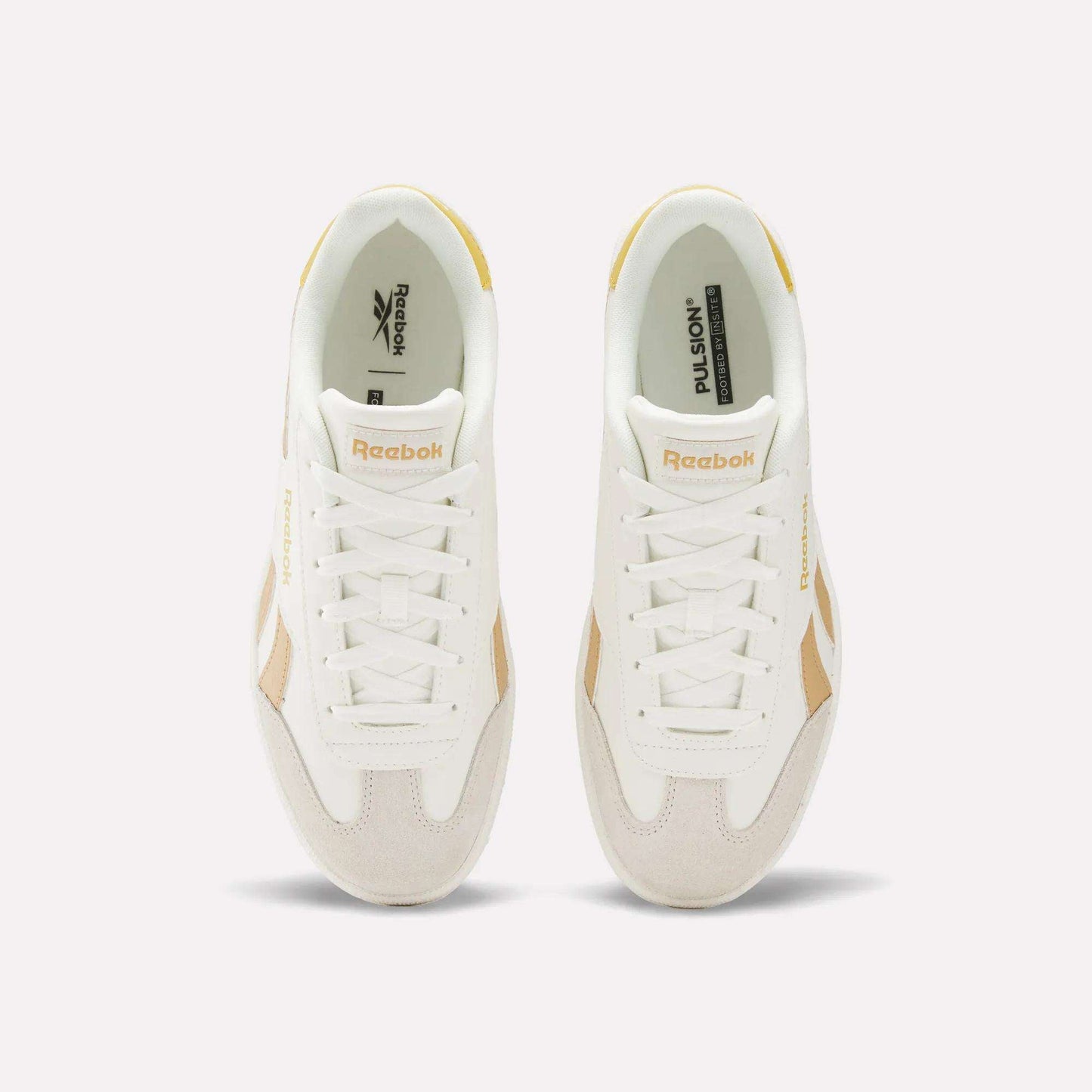 Top view of Reebok Smash Edge Shoes in white with beige details, displaying the Reebok logo on tongue and side, set against a plain light background. Ideal for those seeking stylish and comfortable indoor soccer footwear.