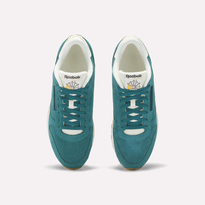 A pair of Classic Leather Shoes by Reebok in teal suede with white accents, shown from above. The image highlights the laces, gold and white branded tongue, beige outsoles, and a light background.