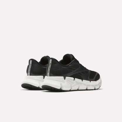 A pair of Reebok Women's FloatZig 2 Running Shoes in black with thick, white segmented soles and Superfloat+ cushioning, displayed from a rear side angle against a plain light background.