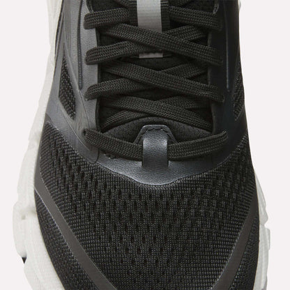 Close-up of the upper part of the Reebok Women's FloatZig 2 Running Shoe in black with mesh fabric, black laces, and gray and white accents on a white sole, featuring Superfloat+ cushioning for comfort.