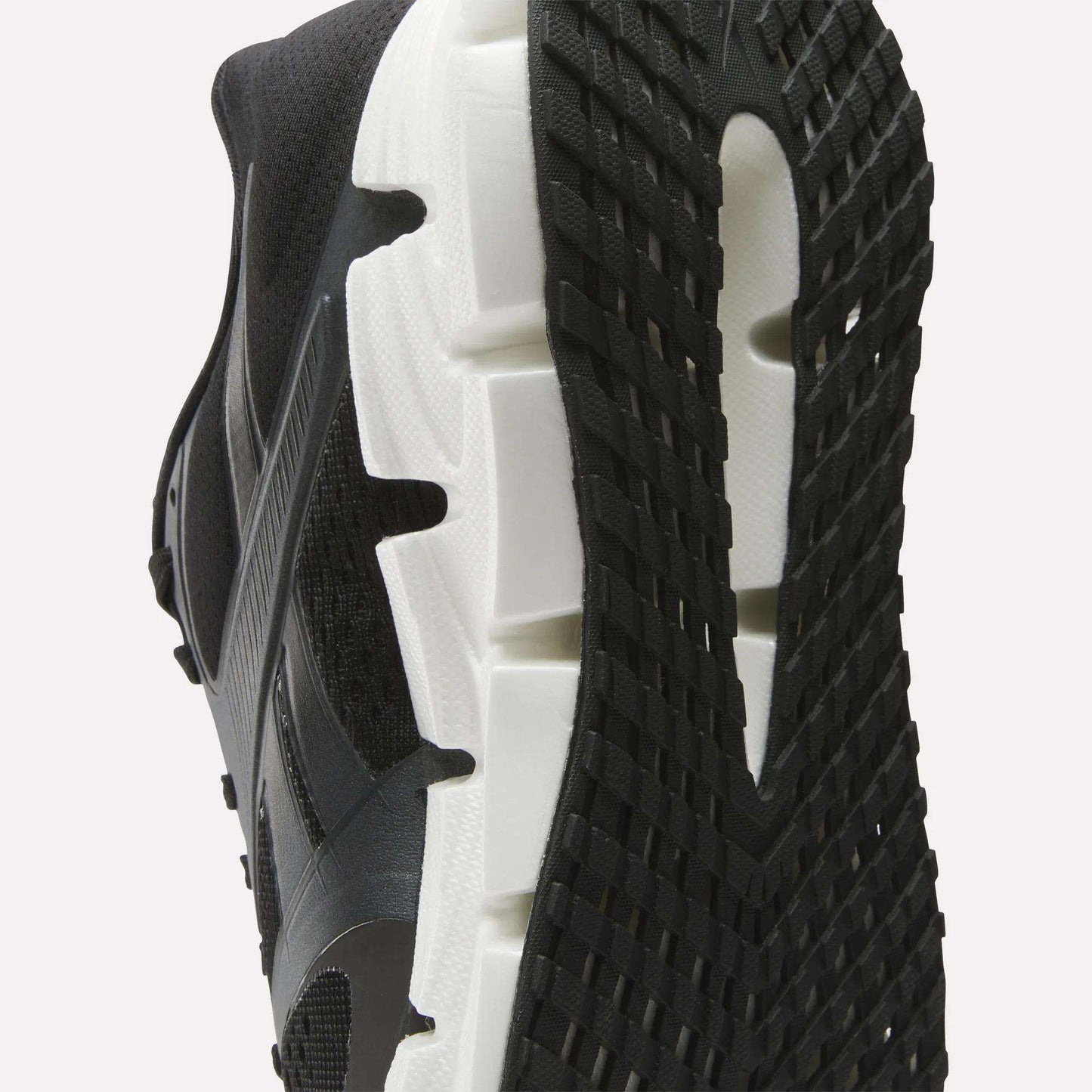 Close-up view of the sole of the Reebok Women's FloatZig 2 Running Shoes, featuring a white midsole, textured black outsole, Superfloat+ cushioning, and detailed tread pattern with signature side design.