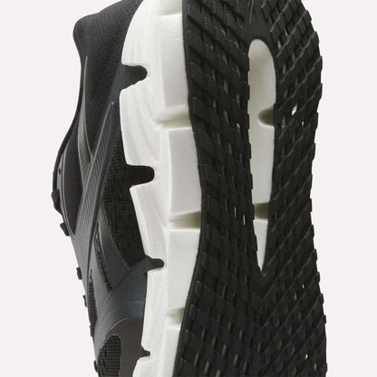 Close-up view of the sole of the Reebok Women's FloatZig 2 Running Shoes, featuring a white midsole, textured black outsole, Superfloat+ cushioning, and detailed tread pattern with signature side design.