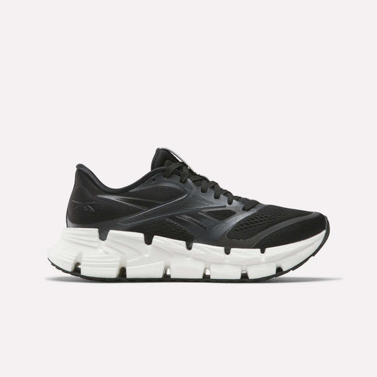 The Women's FloatZig 2 Running Shoes by Reebok are black, feature mesh and synthetic overlays, a chunky white segmented sole with Superfloat+ cushioning, and are shown from the side on a plain white background.