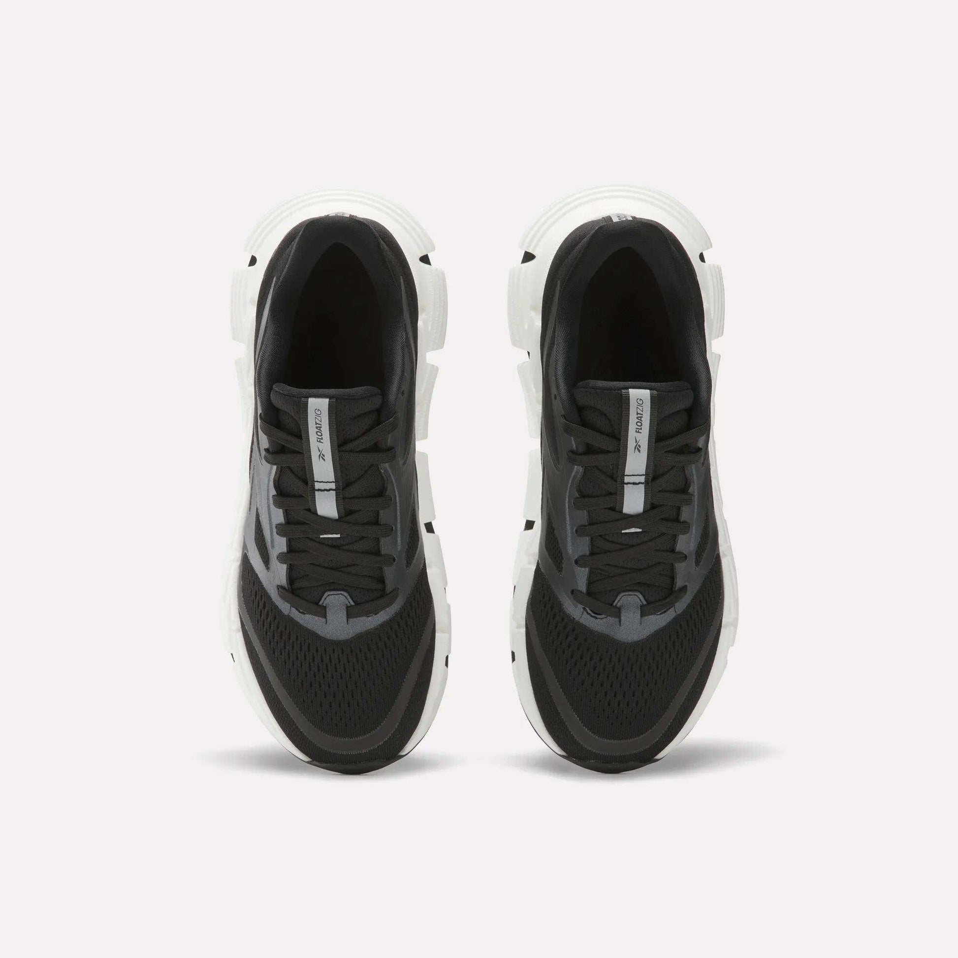 A pair of Women's FloatZig 2 Running Shoes by Reebok in black and white, shown from above with black laces, mesh uppers, and thick white soles featuring Superfloat+ cushioning on a plain white background.