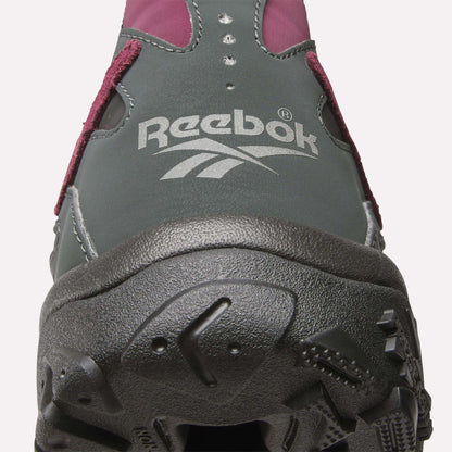 Close-up of the front of a dark grey Reebok Preseason 94 Low Retro Basketball Shoe, featuring a white Reebok logo on the upper, maroon accents, and a rugged black sole—a modern update to classic '90s style.