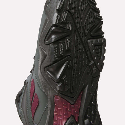 Close-up view of the sole and side of a dark gray and maroon Reebok Preseason 94 Low Retro Basketball Shoe, showing its aggressive tread pattern and textured rubber for superior grip.