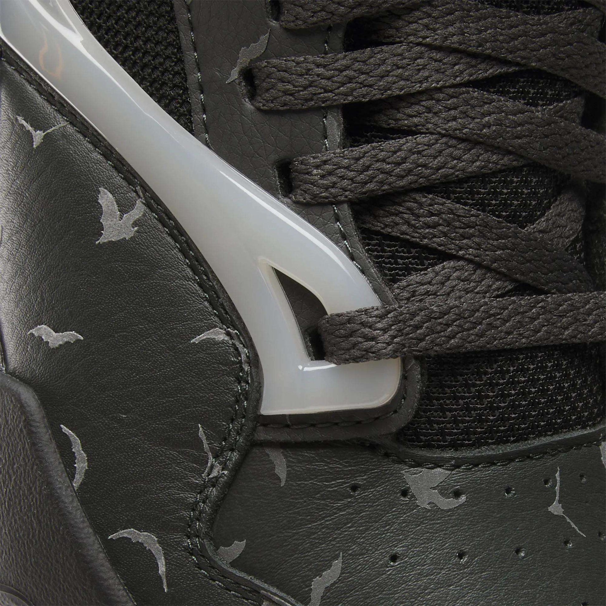 Close-up of the Reebok Pump Omni Zone II Retro Basketball Shoes featuring dark leather, black textured laces, glossy white plastic accents, reflective details, and a light gray bat pattern printed on the leather.