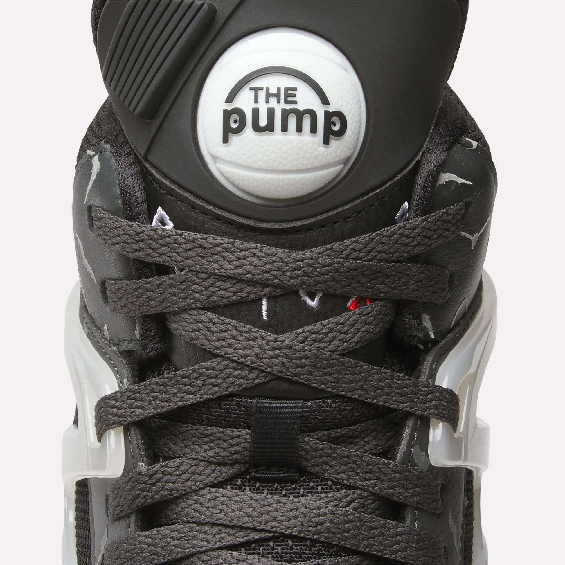 Close-up of Reebok Pump Omni Zone II Retro Basketball Shoes featuring dark gray laces, a round white "The Pump" button on the tongue, white plastic lace holders, and subtle reflective accents on the sides.