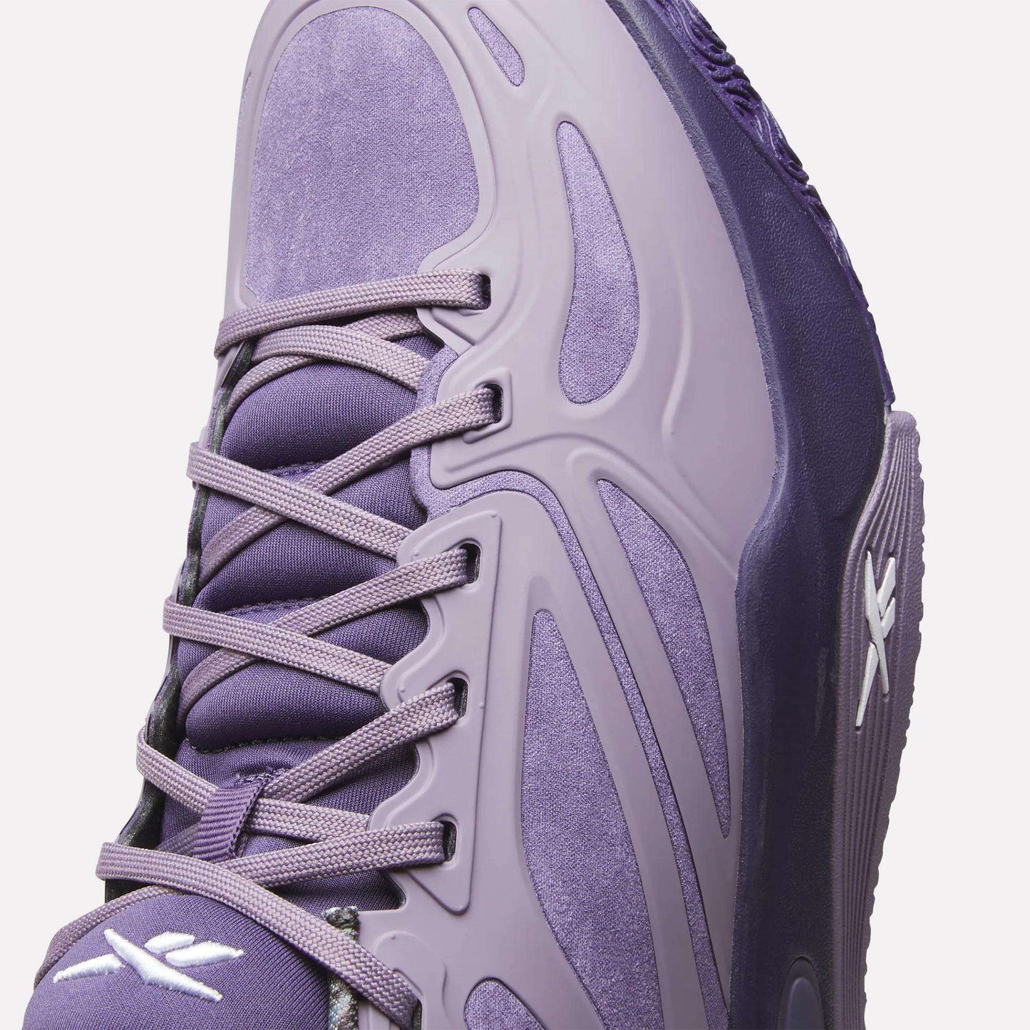 Close-up of the Reebok Engine A Basketball Shoes in purple suede with synthetic overlays, purple laces, and white Reebok logos. Modern curved lines and ERS technology deliver comfort and style inspired by performance basketball shoes.