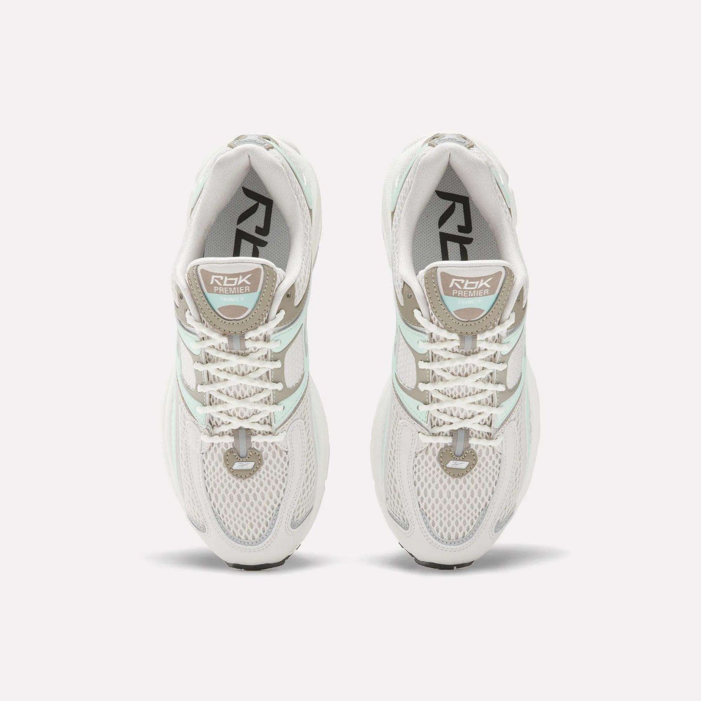 Top view of Reebok Women's Premier Trinity Shoes in white with gray and light green accents, mesh panels, and RBK branding—highlighting retro tech style on a clean white background.