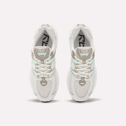 Top view of Reebok Women's Premier Trinity Shoes in white with gray and light green accents, mesh panels, and RBK branding—highlighting retro tech style on a clean white background.