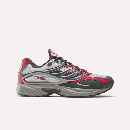 The Reebok Premier Road Control Shoes are shown in a side profile on a plain white background, featuring red, white, and gray colors with black accents, mesh panels, and the signature Reebok logo on the side.