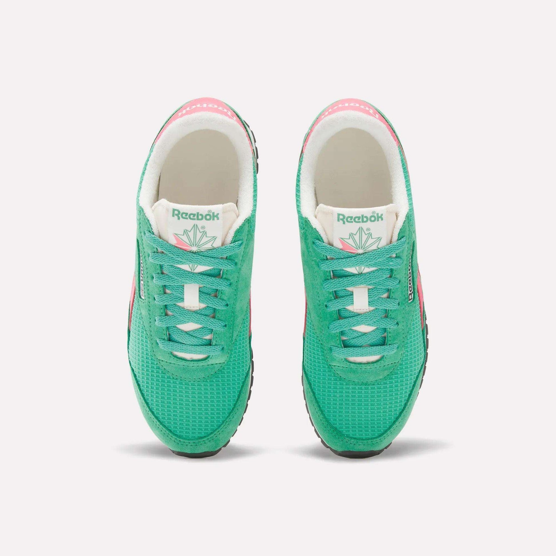 A top view of Reebok Women's Classic AZ Shoes in green, featuring white tongues, black soles, and pink accents on the sides and heels—an ideal pick for retro running shoe fans, displayed against a plain white background.