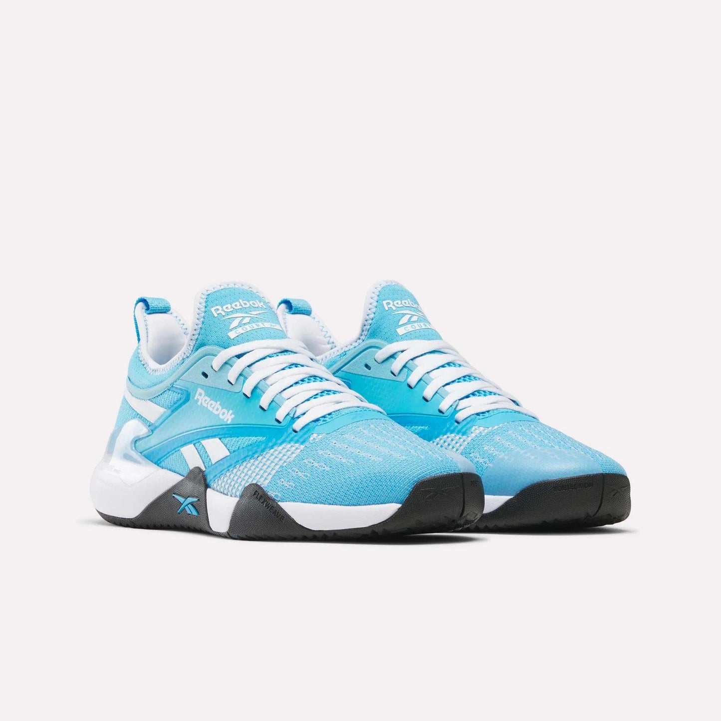 A pair of Reebok Nano Court Shoes in light blue and white with black soles for multidirectional traction, white laces, and Reebok logos on the sides and tongues, displayed on a plain white background.
