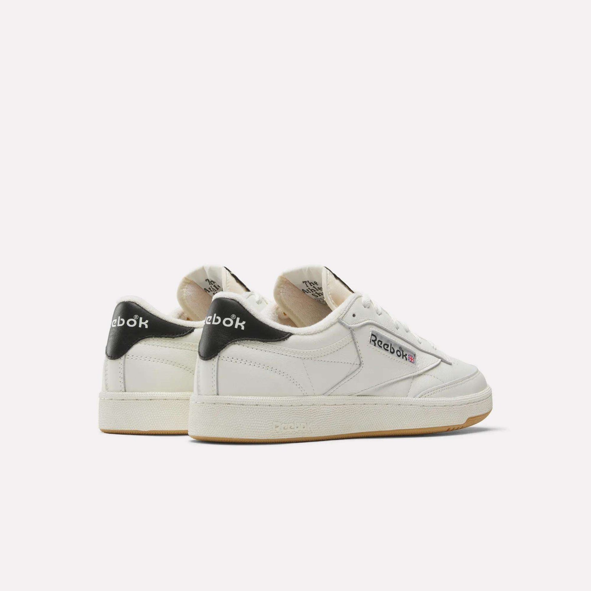 A pair of white Reebok Club C 85 Vintage Shoes with black heel accents, beige outsoles, and the Reebok logo on the sides. The durable leather upper is displayed at an angle, showing both the side and back.