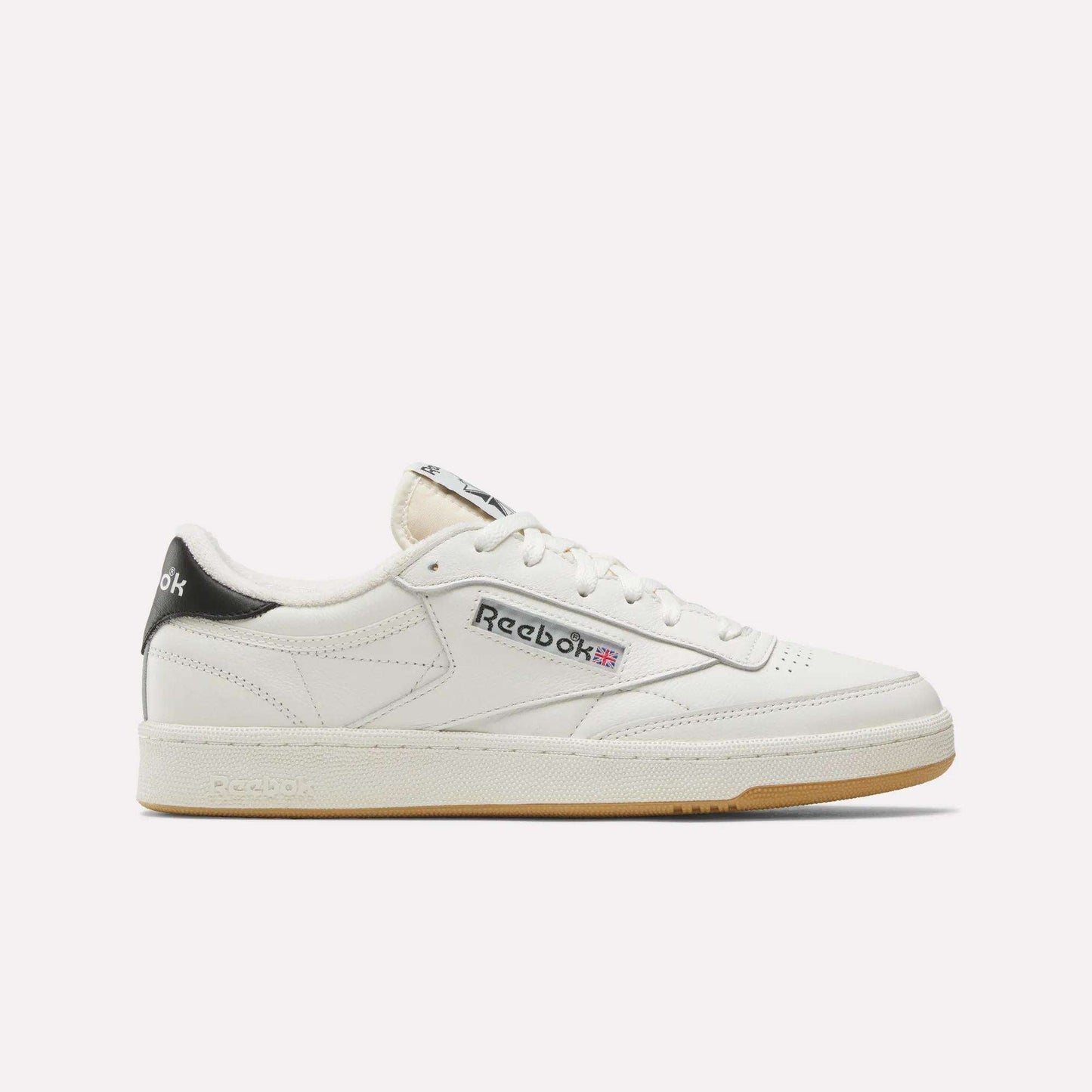The Reebok Club C 85 Vintage Shoes feature a white leather upper, black heel tab, cream sole, and Reebok branding in black and red on the side. Shown on a white background, they deliver lightweight cushioning for all-day comfort.