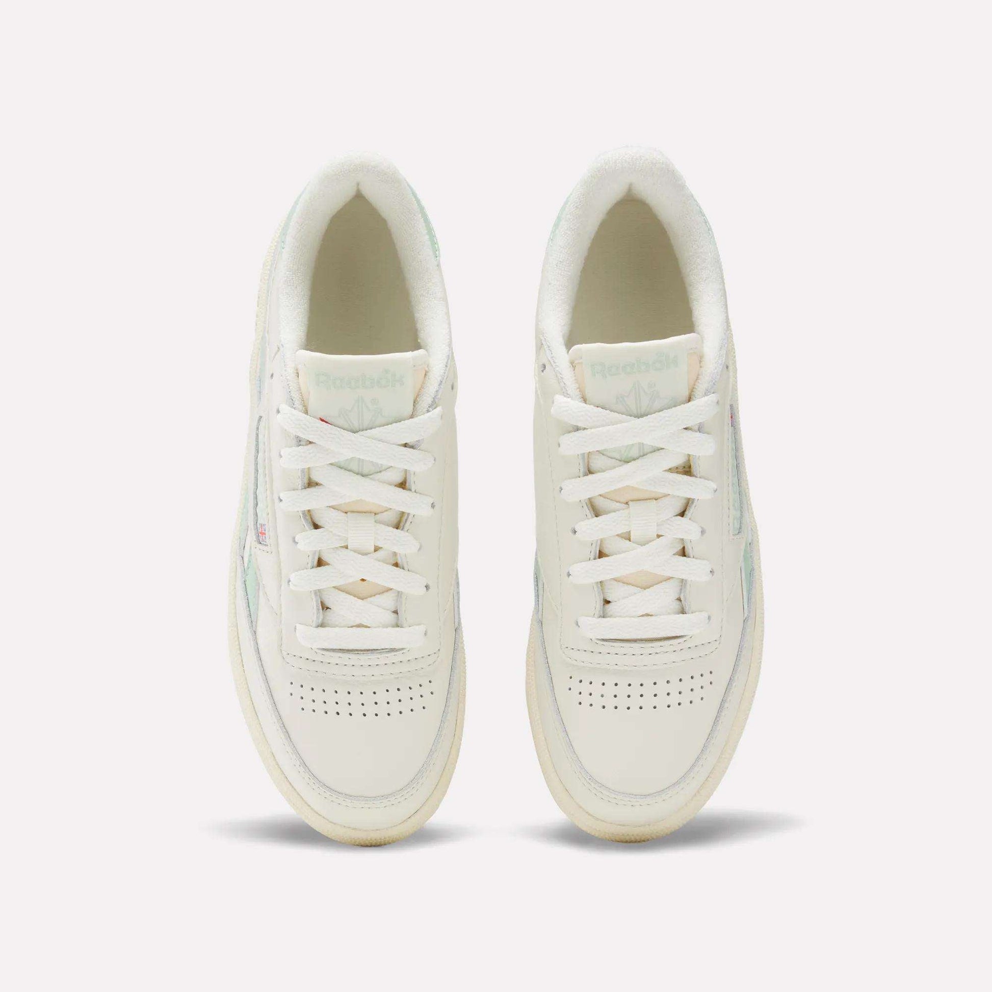 A pair of Women's Club C Revenge Vintage Shoes by Reebok in white with light green accents, shown from above. Features include white laces, perforated toe boxes, and the visible Reebok logo on the tongues.