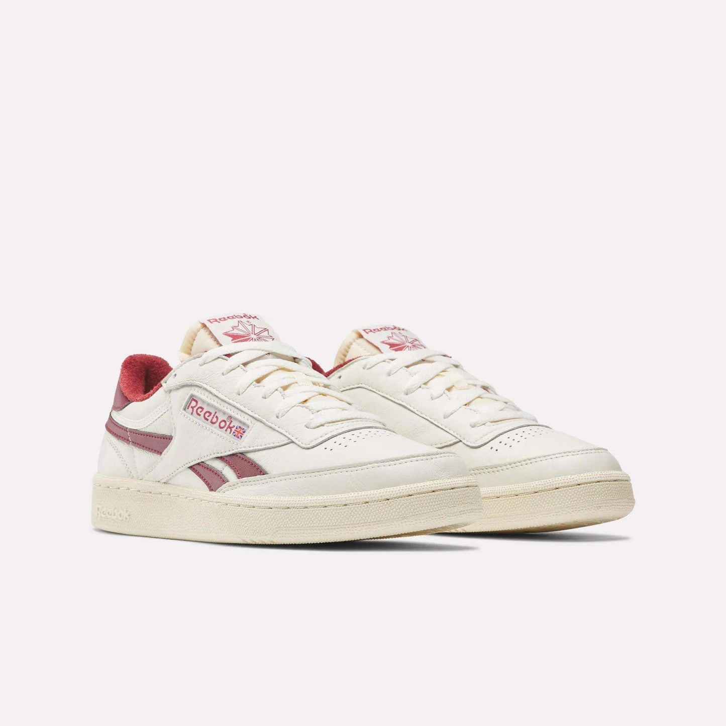 The Reebok Club C Revenge Vintage Shoes feature off-white full-grain leather with maroon logo, stripes, and lining accents. These low-top sneakers offer a retro design and beige sole for a classic look.