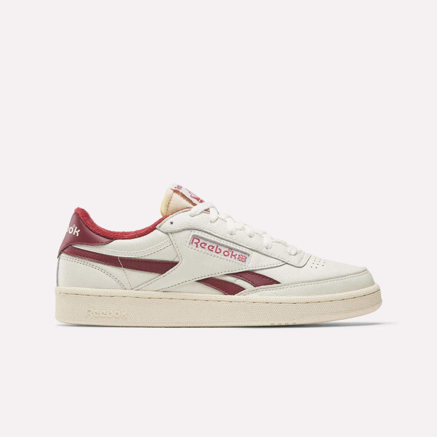 The Reebok Club C Revenge Vintage Shoes feature full-grain white leather, maroon logo, heel, and side stripes, white laces, a beige sole, and retro styling inspired by vintage classics.