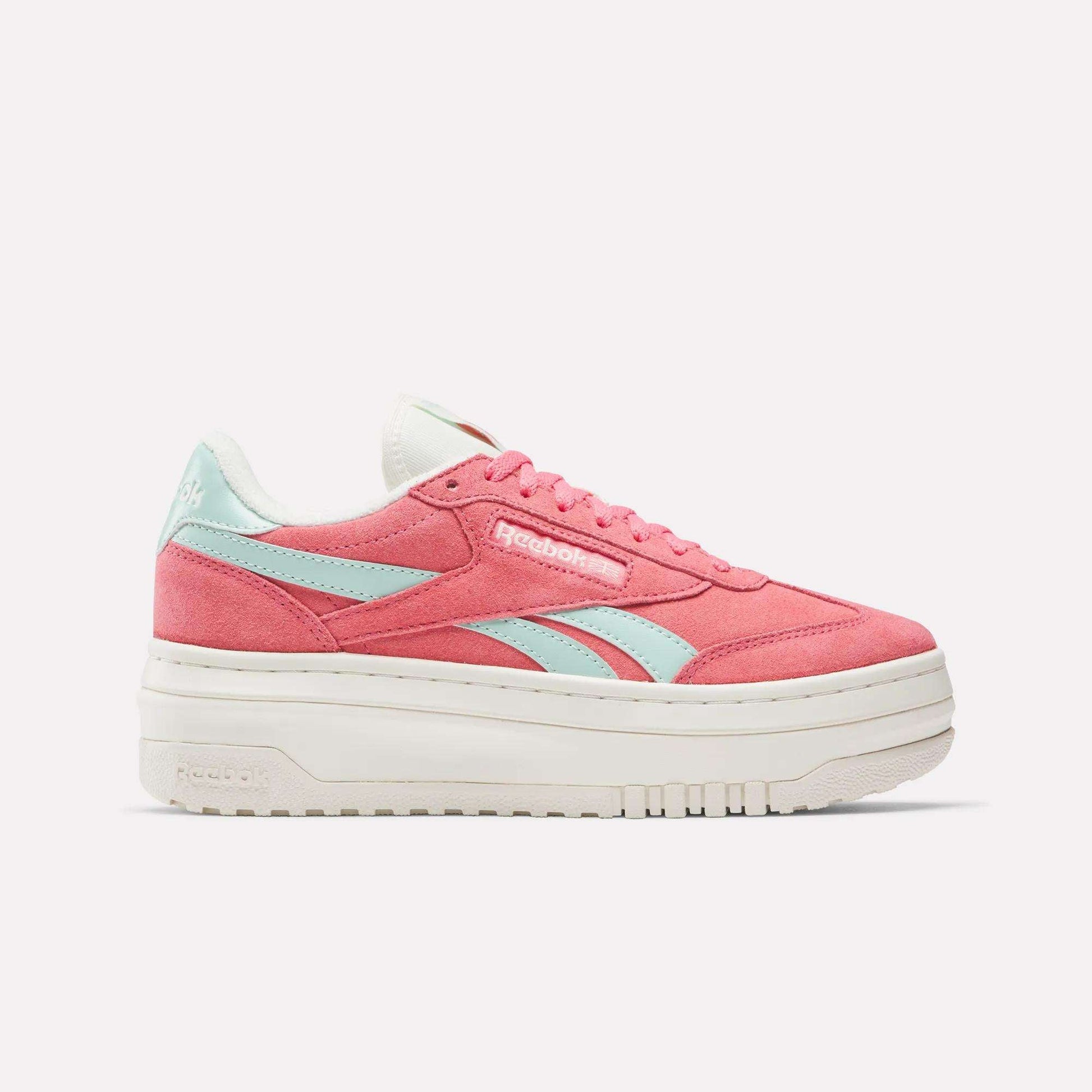 The Reebok Campio Extra Women's Shoes are shown in pink with light blue side stripes, white laces, and a thick platform midsole, displayed in side profile against a plain white background.