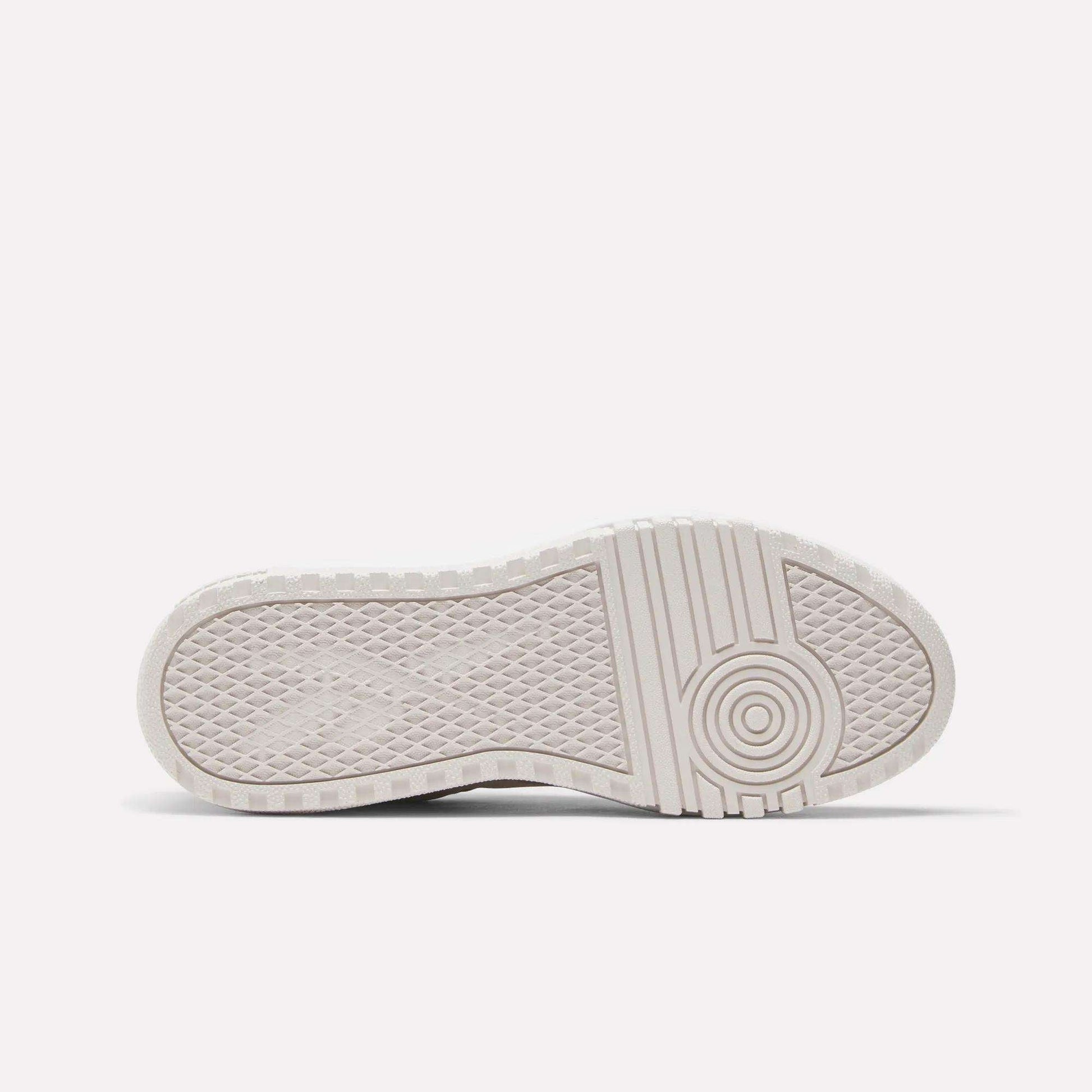 The image displays the bottom view of the Reebok Women's Campio Extra Shoes, highlighting a white platform sole with a textured tread featuring diamond shapes on the left and circular patterns on the right for enhanced grip and traction.