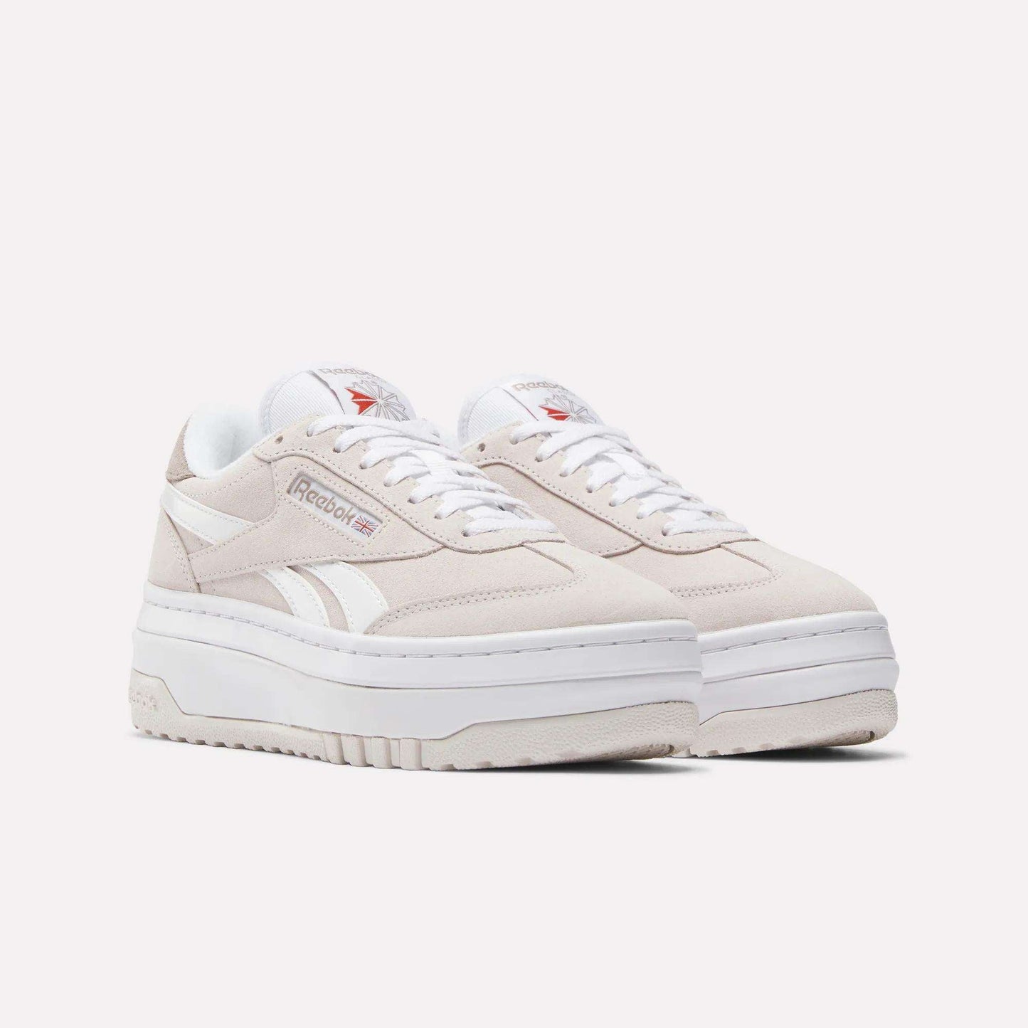 A pair of Women's Campio Extra Shoes by Reebok in beige, featuring white accents, thick white soles, white laces, and the Reebok logo on the sides and tongue, displayed on a plain white background.