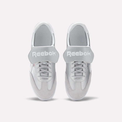 A pair of Reebok Campio XT Kilty Shoes in white leather are shown from above, side by side on a plain white background. They feature laces, wide velcro straps across the top, and the Reebok logo in white text.