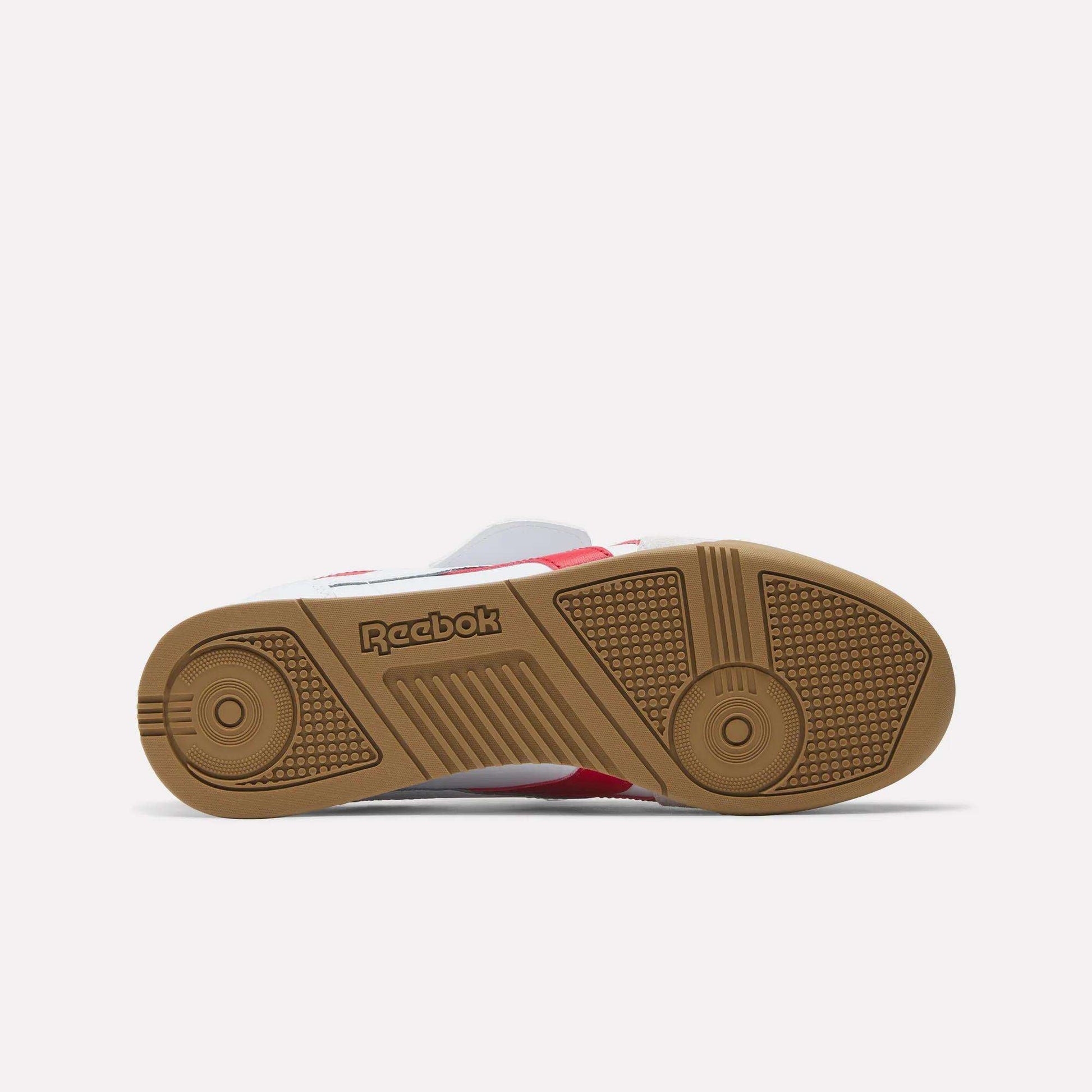 The image displays the sole of the Reebok Campio XT Kilty Shoes, showcasing a gum-colored, textured rubber grip and a central Reebok logo. Inspired by classic tennis style, it is set against a plain white background.