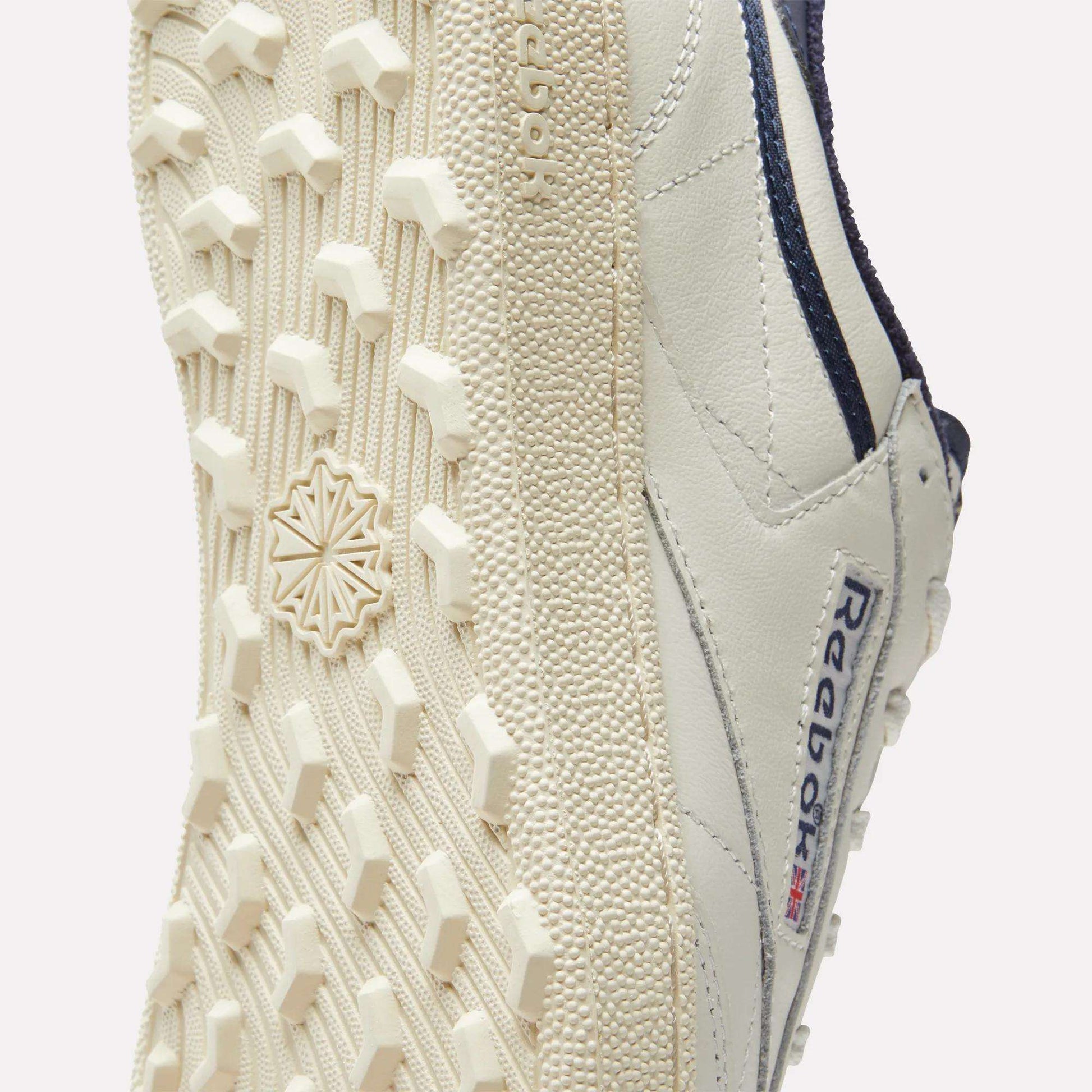 Close-up of the sole and side of the Reebok Men's Club C Golf Shoes, showcasing a spikeless outsole with hexagonal tread and Reebok logo—delivering classic golf style and comfort.