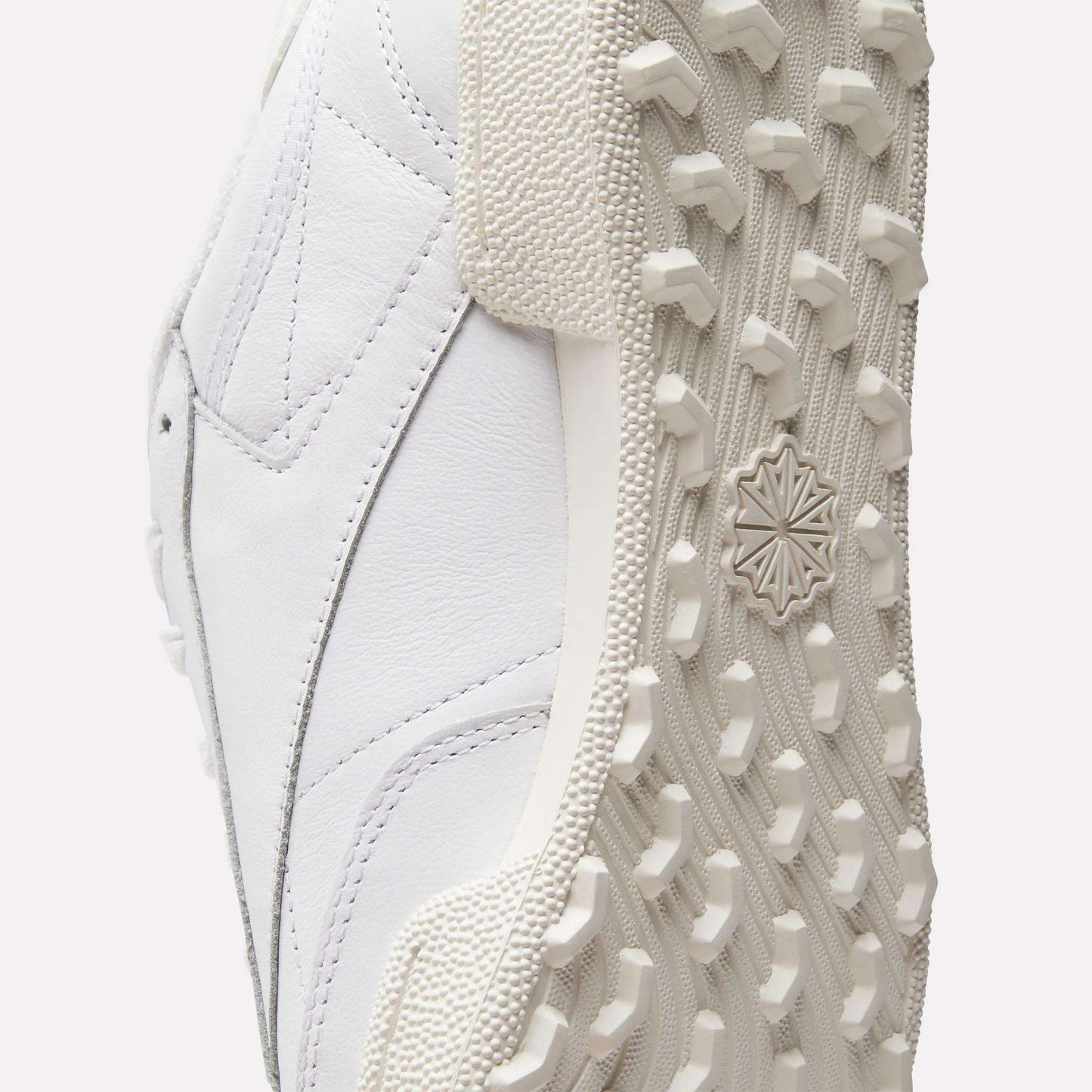Close-up of the Reebok Men's Club C Golf Shoes shows a spikeless outsole with detailed tread and textured rubber, plus stitching and paneling on the water-resistant leather upper.
