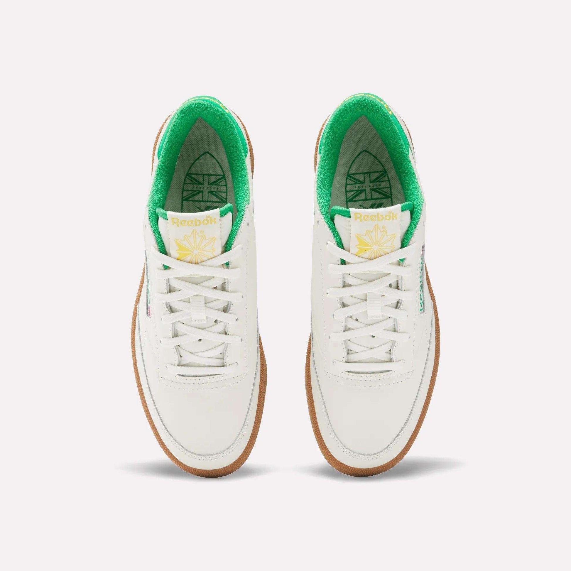 The Reebok Men's Club C Golf Shoes feature a white, water-resistant leather upper, green inner lining, white laces, gum soles, spikeless outsole, and yellow-green tongue branding—shown from above on a plain background.