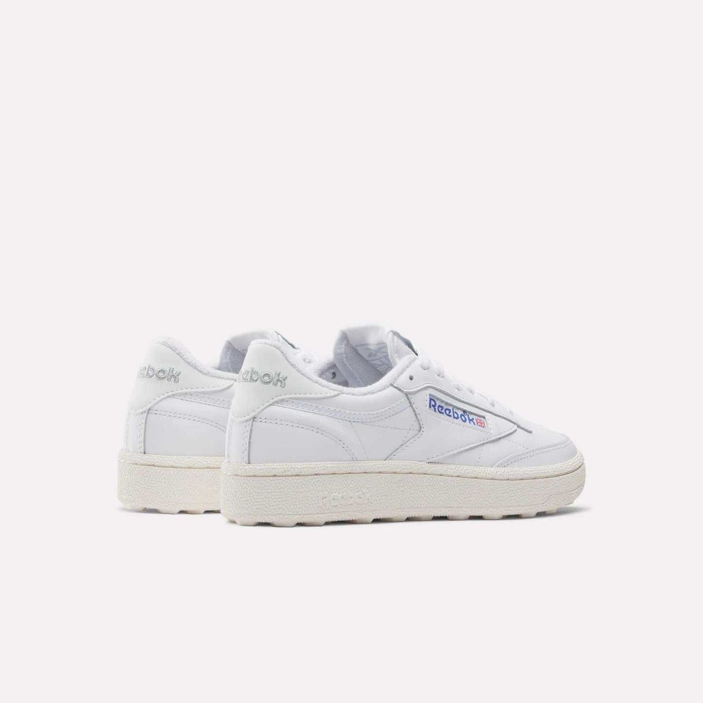 The Women's Club C Golf Shoes by Reebok are classic white sneakers with off-white soles and a spikeless outsole, featuring the Reebok logo on the side and heel. They are photographed against a plain white background.