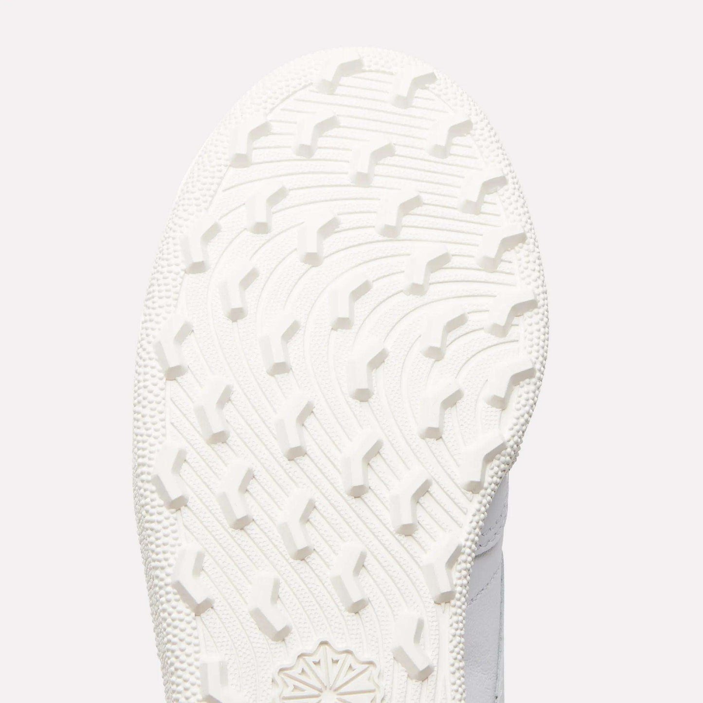 Close-up of the white sole on Reebok Women's Club C Golf Shoes, showing a curved, textured tread with raised angular grips on its spikeless outsole.