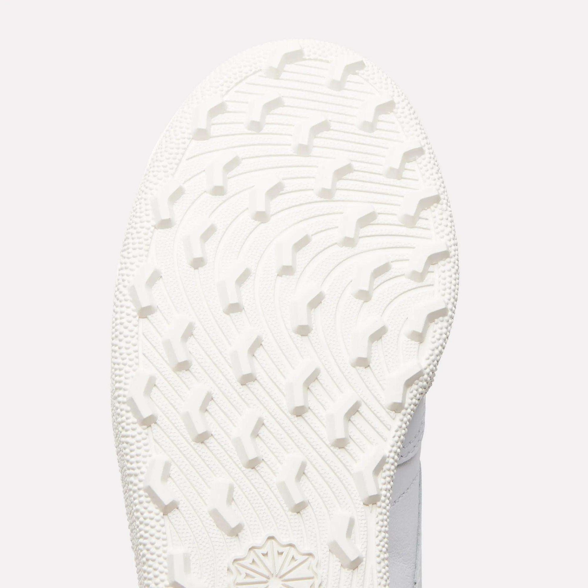 Close-up of the white sole on Reebok Women's Club C Golf Shoes, showing a curved, textured tread with raised angular grips on its spikeless outsole.