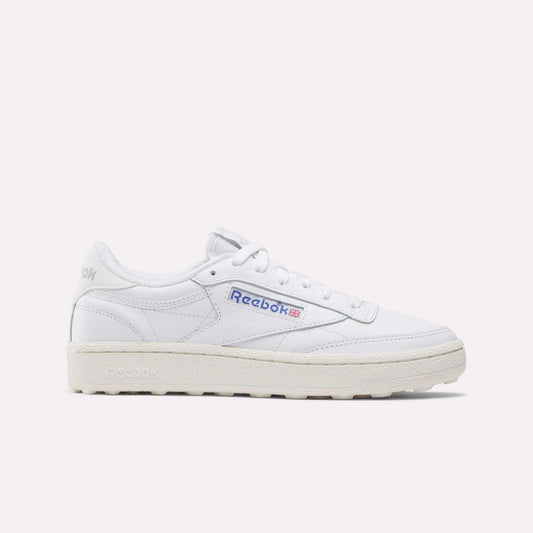 The Reebok Women’s Club C Golf Shoes feature a white upper, cream sole, blue and red side logo, spikeless outsole, and white laces, shown against a plain white background.