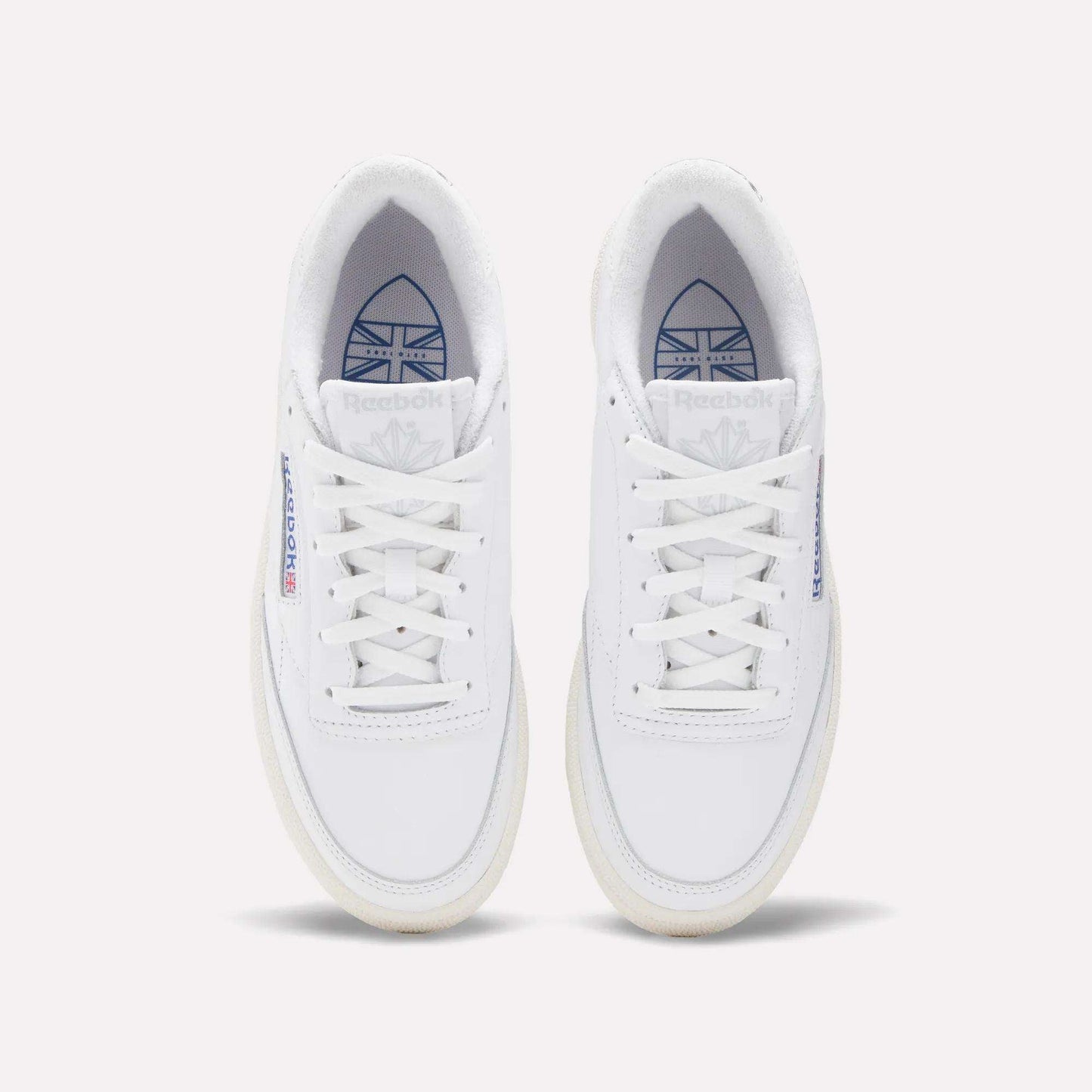 Top view of Reebok Women's Club C Golf Shoes in water-resistant leather, featuring white sneakers with blue and red branding on the tongue and side, displayed side by side on a plain white background.