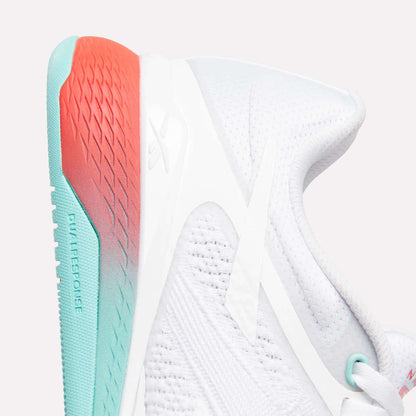 Close-up of Reebok Women's Nano X5 Training Shoes featuring a white, textured mesh upper for breathability and a comfy sole fading from turquoise at the heel to coral red at the back, with subtle branding on the side and heel.