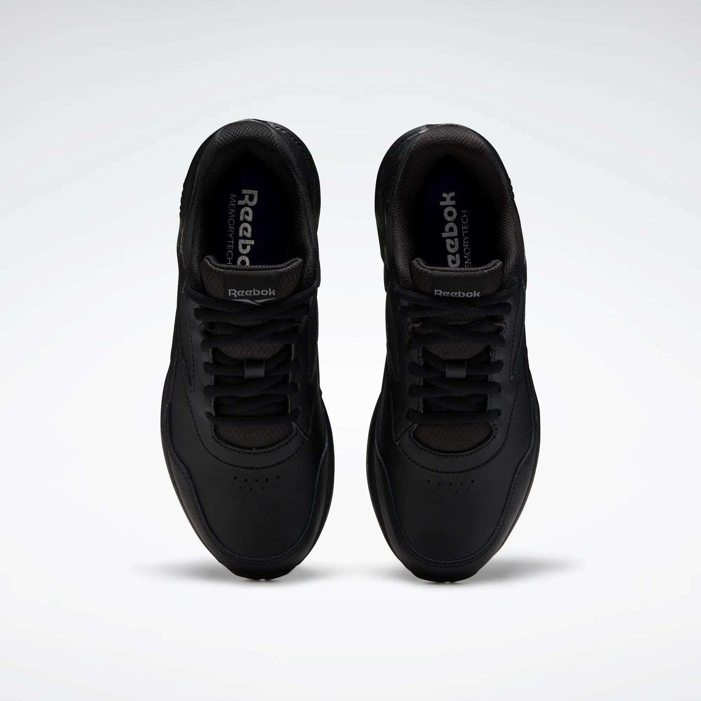 A pair of Women's Walk Ultra 7 DMX Max Walking Shoes by Reebok, shown from above with black laces and a minimalist design featuring DMX cushioning for comfort, set against a plain white background.