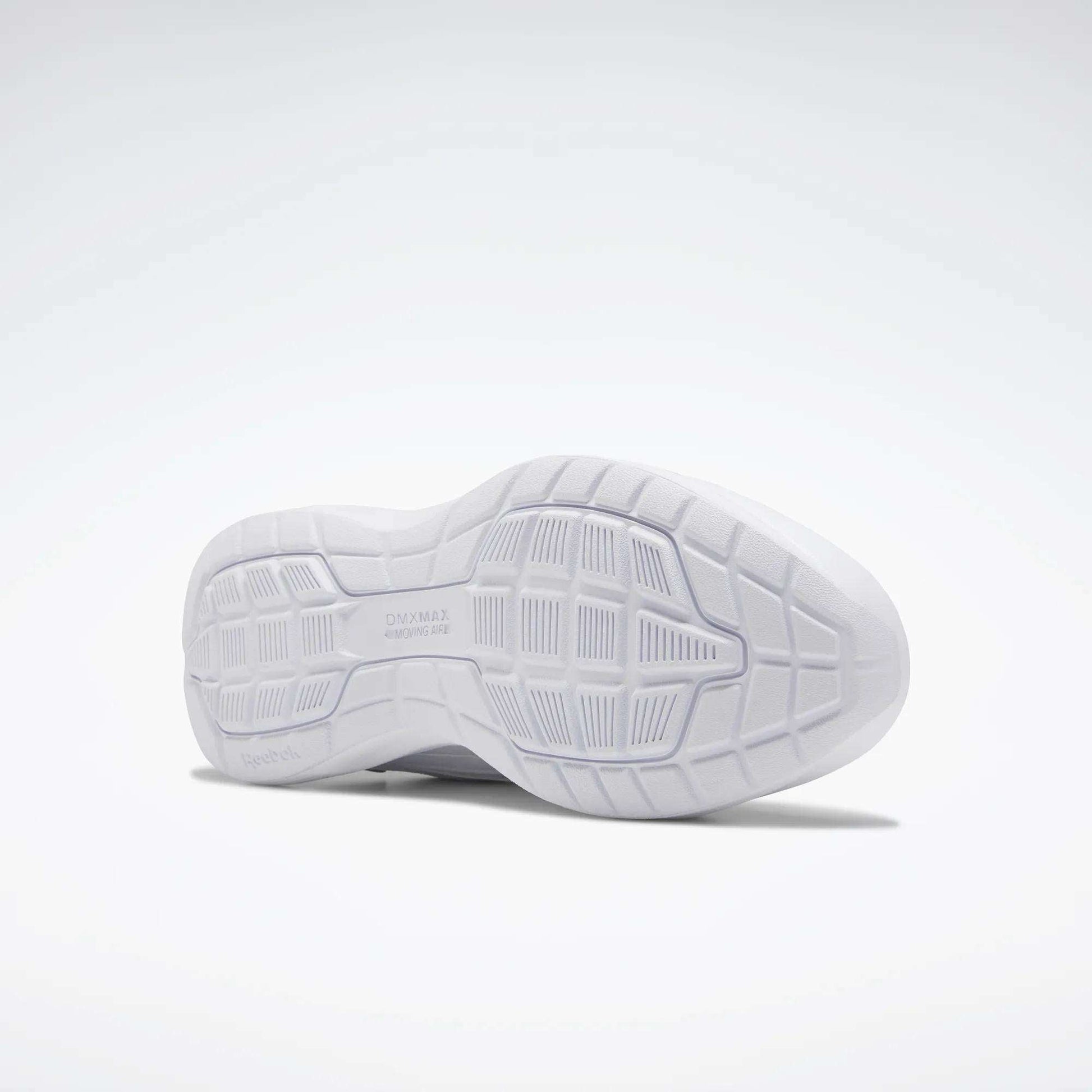The image shows the sole of a Reebok Women's Walk Ultra 7 DMX Max Walking Shoe. Its white, textured grip and DMX cushioning enhance comfort. The shoe is positioned on its side against a plain, light background.