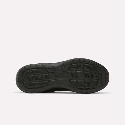 Black sole with geometric tread patterns and grooves, shown from below against a white background. Designed for grip and durability, this sole is typical of cushioned Reebok Walk Ultra 7 DMX Max Walking Shoes.