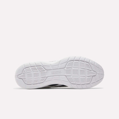 The image displays the white rubber outsole of Reebok Walk Ultra 7 DMX Max Walking Shoes, featuring a patterned tread with grooves and geometric shapes for traction. "DMX MAX" and "Reebok" are embossed, emphasizing their cushioned comfort.