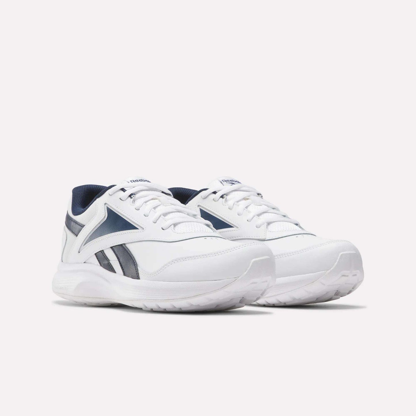 The Reebok Walk Ultra 7 DMX Max Walking Shoes feature white uppers with navy accents, breathable mesh panels, and a bold side logo, shown against a plain white background.