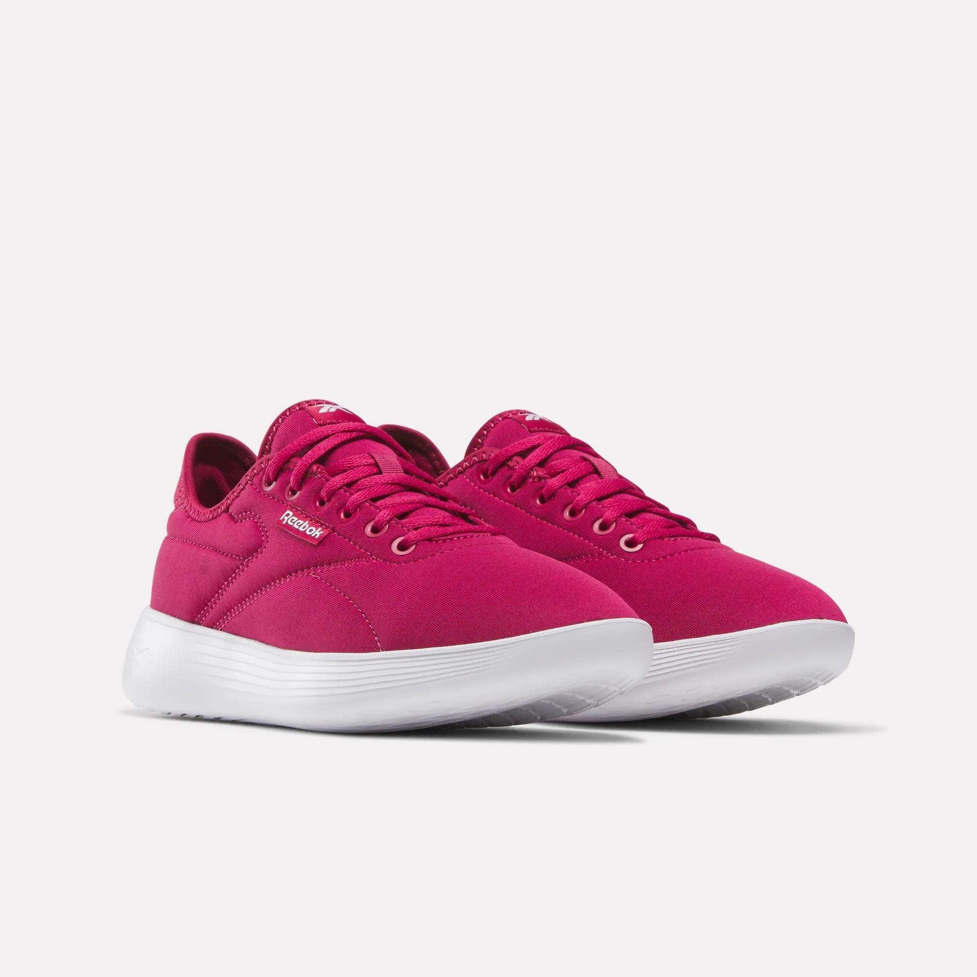 A pair of Women's Active Lite Shoes by Reebok in bright pink with white soles, featuring laces and a simple, modern design, shown at an angle on a plain light background.
