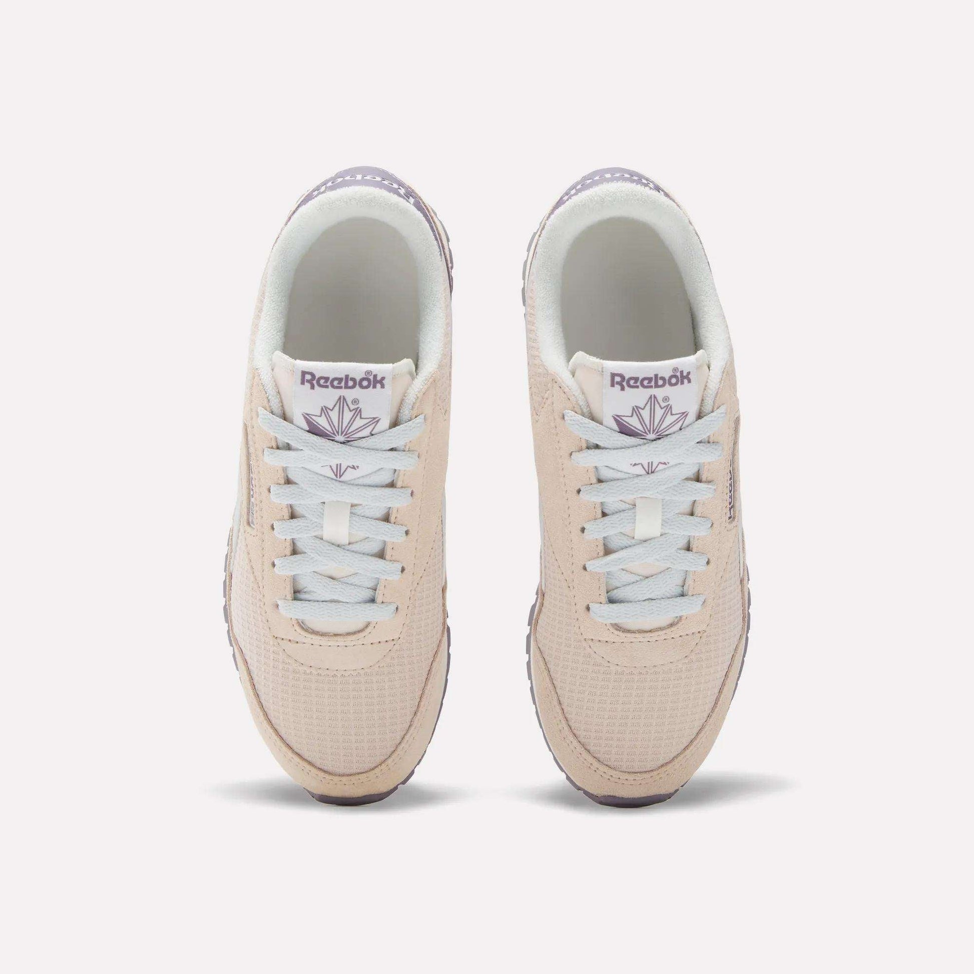 The Women's Classic AZ Shoes by Reebok are beige with white laces and light purple branding, shown from above on a white background—ideal for fans of 70s-style sneakers.