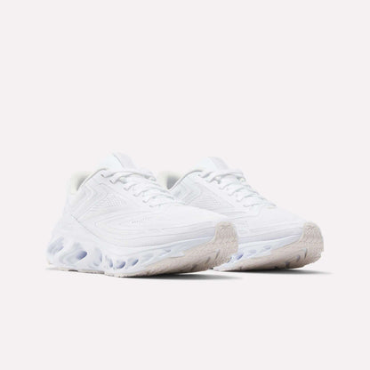 The Reebok Women's Fuel Flex Run Shoes in white feature textured soles and wavy Fuel Flex midsoles, shown against a light background.