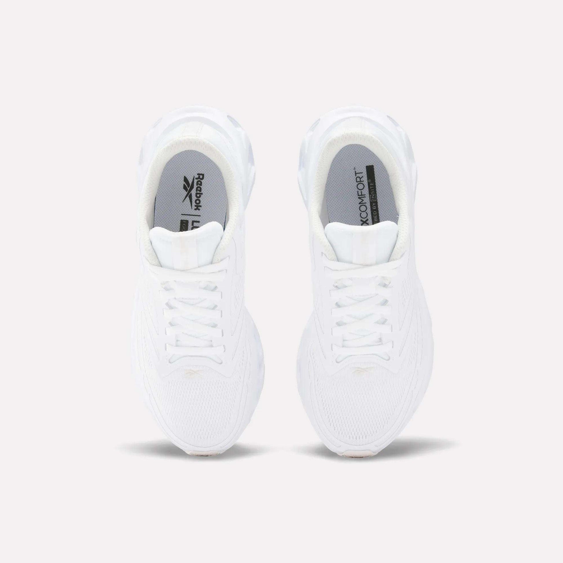 Top view of Reebok Women's Fuel Flex Run Shoes in white with white laces, gray insoles featuring the Reebok logo and "MEMORY TECH" text, and a plush Fuel Flex midsole, set on a plain light background.