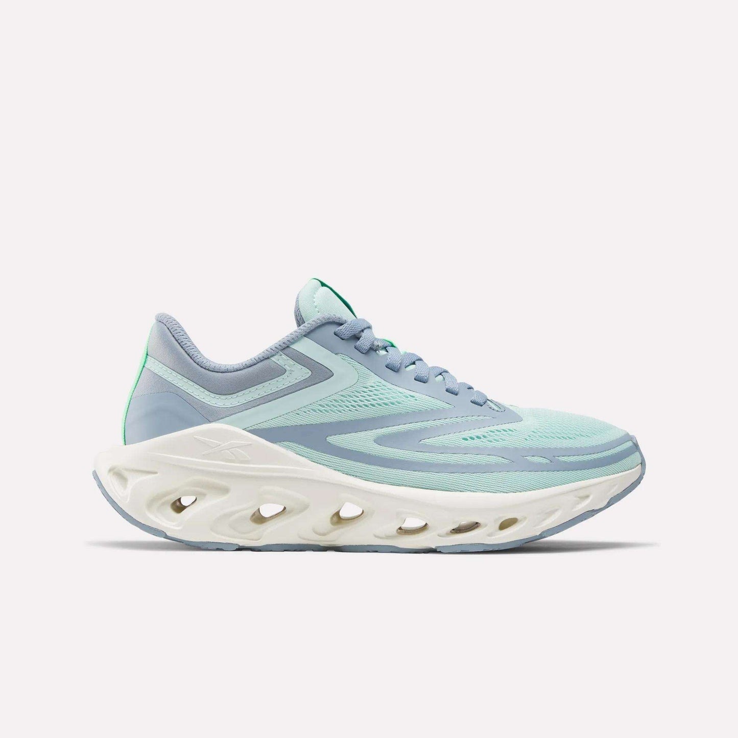 The Women's Fuel Flex Run Shoes by Reebok feature a light blue and mint green design with a thick white sole and oval cutouts, built for long-lasting comfort, shown from the side on a plain white background.